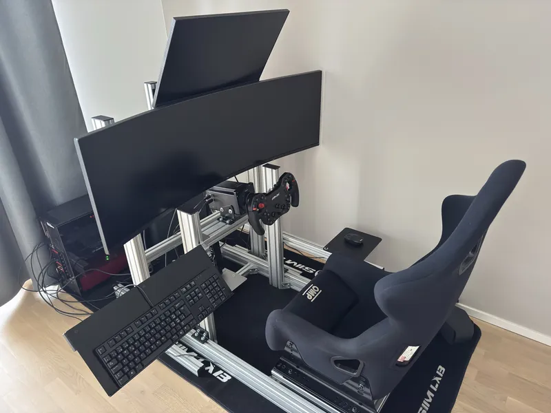 Driving simulator with bucket seat, wheel base and screens